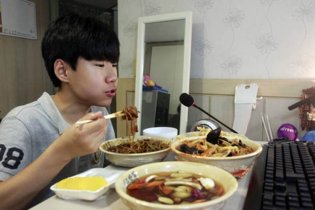 In this Monday, Aug. 17, 2015 photo, Kim Sung-jin, 14, broadcasts himself eating delivery Chinese food in his room at home in Bucheon, south of Seoul, South Korea. Every evening, he gorges on food as he chats before a live camera with hundreds, sometimes thousands, of teenagers watching. Thatís the show, and it makes Kim money: 2 million won ($1,700) in his most successful episode. Better known to his viewers by the nickname Patoo, he is one of the youngest broadcasters on Afreeca TV, an app for live-broadcasting video online launched in 2006. (AP Photo/Julie Yoon)