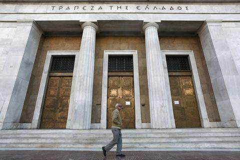 An elderly man walks outside the Bank of Greece in Athens