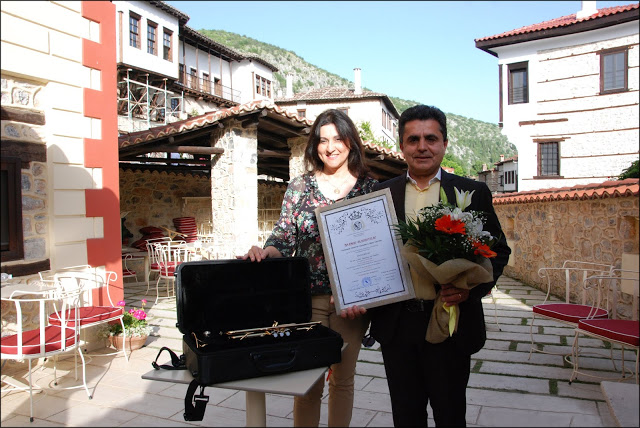 Ο συμπολίτη μας κ. Ζήσης Τζηκαλάγιας, ιατρός, μετά της συζύγου του, στον αύλειο χώρο του Ξενώνα «Αρχοντικό Ωρολογόπουλου», με το «Βραβείο Φιλομουσίας» της Ακαδημίας Γραμμάτων και Τεχνών Καστοριάς «Θωμάς Μανδακάσης» και το μουσικό όργανο της δωρεάς του για την υποστήριξη του Τμήματος Φιλαρμονικής της Ακαδημίας και του Δήμου Καστοριάς.