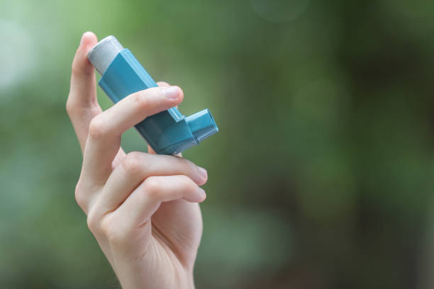 View of a man's hand holding a blue asthma inhaler